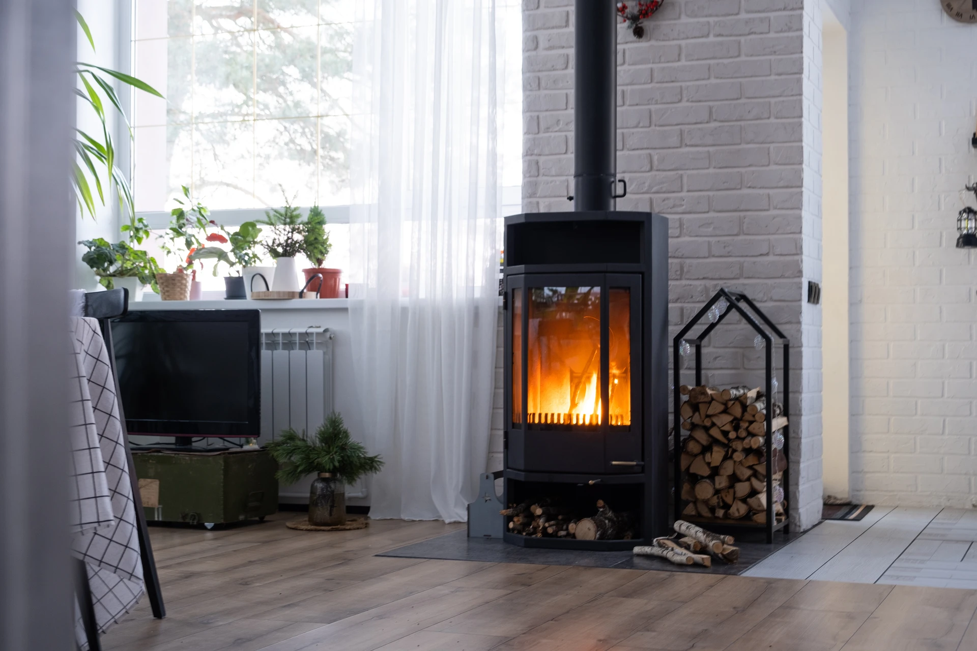 Poêle à bois design contemporain en acier émaillé noir brillant, vitre ovale frontale révélant un foyer actif avec flammes vives